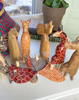 A set of handmade wooden animals surrounding a table on a white shelf