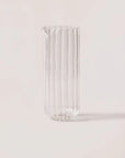 Clear glass vase with ribbed design on a light pink background