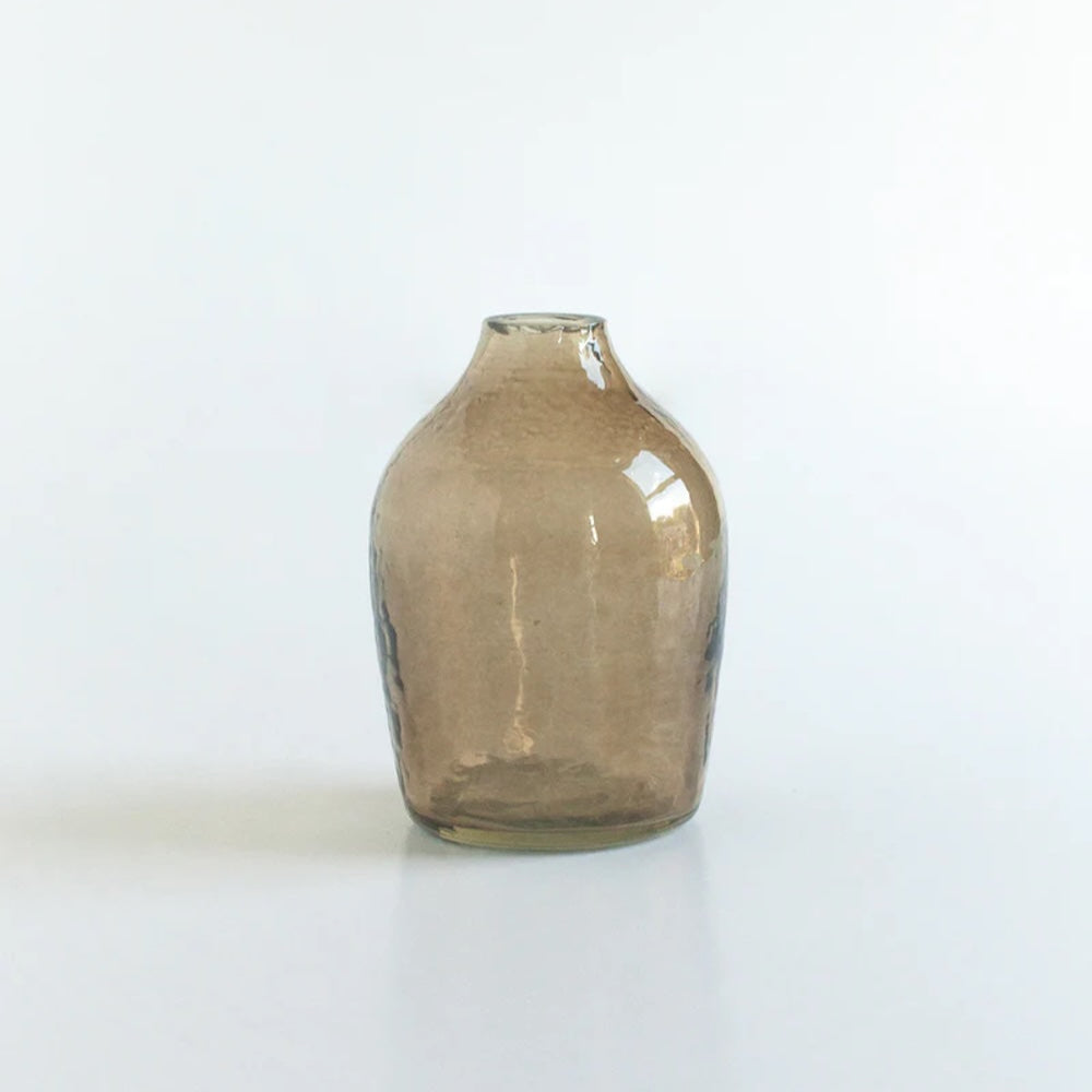 A brown hand-hammered glass bud vase on a white background.