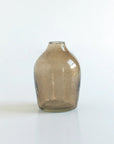 A brown hand-hammered glass bud vase on a white background.