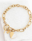 Gold chain bracelet with heart and tag charms on a white background