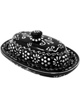A black and white handcrafted pottery butter dish with floral patterns