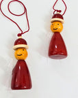 Two wooden Christmas ornaments designed as santa's elves wearing Santa hats on a white background.