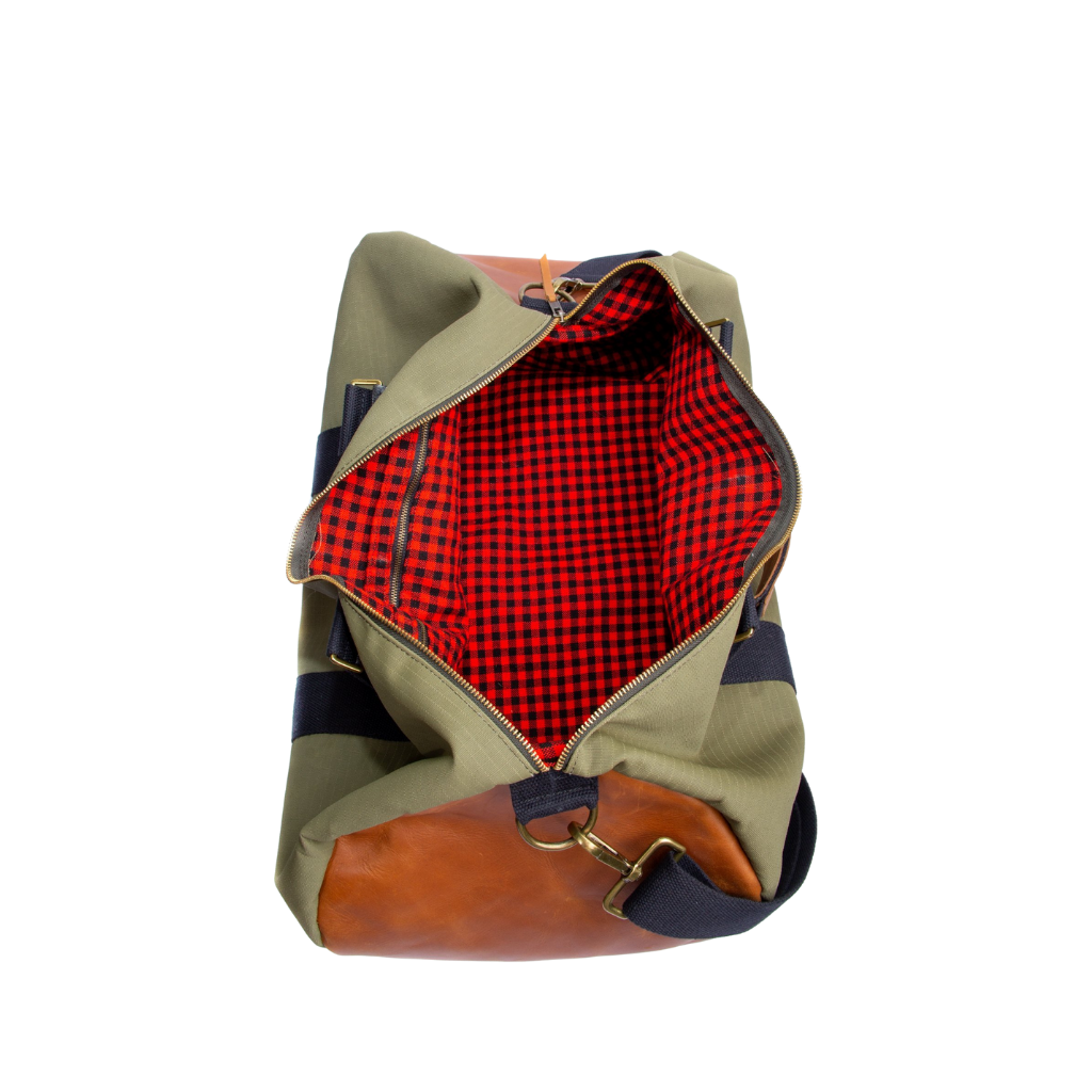 The inside of a green and brown duffel bag with black straps and a tan leather bottom, standing upright on a plain background.