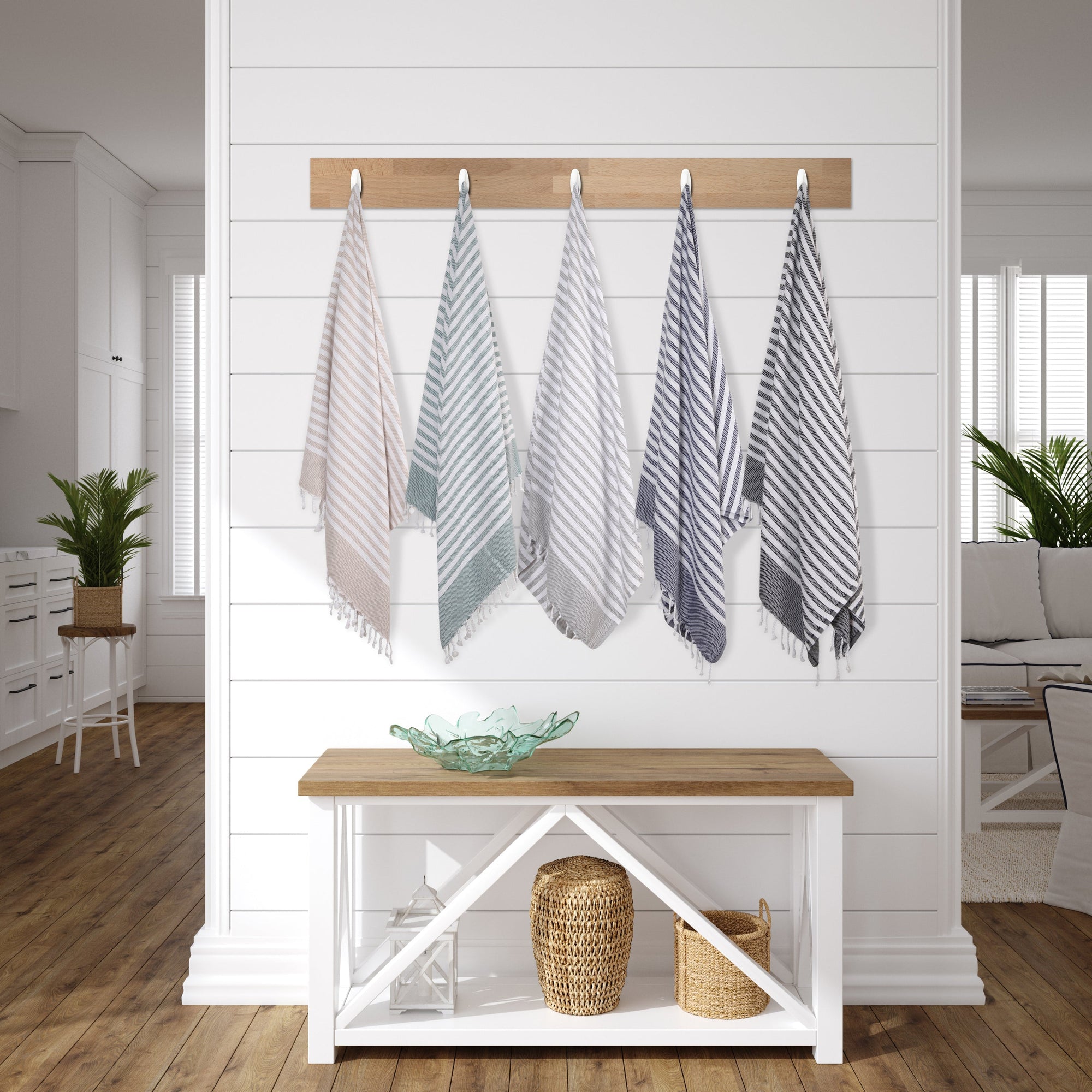 Set of five striped towels hanging on a rack against a white wall with a wooden bench below