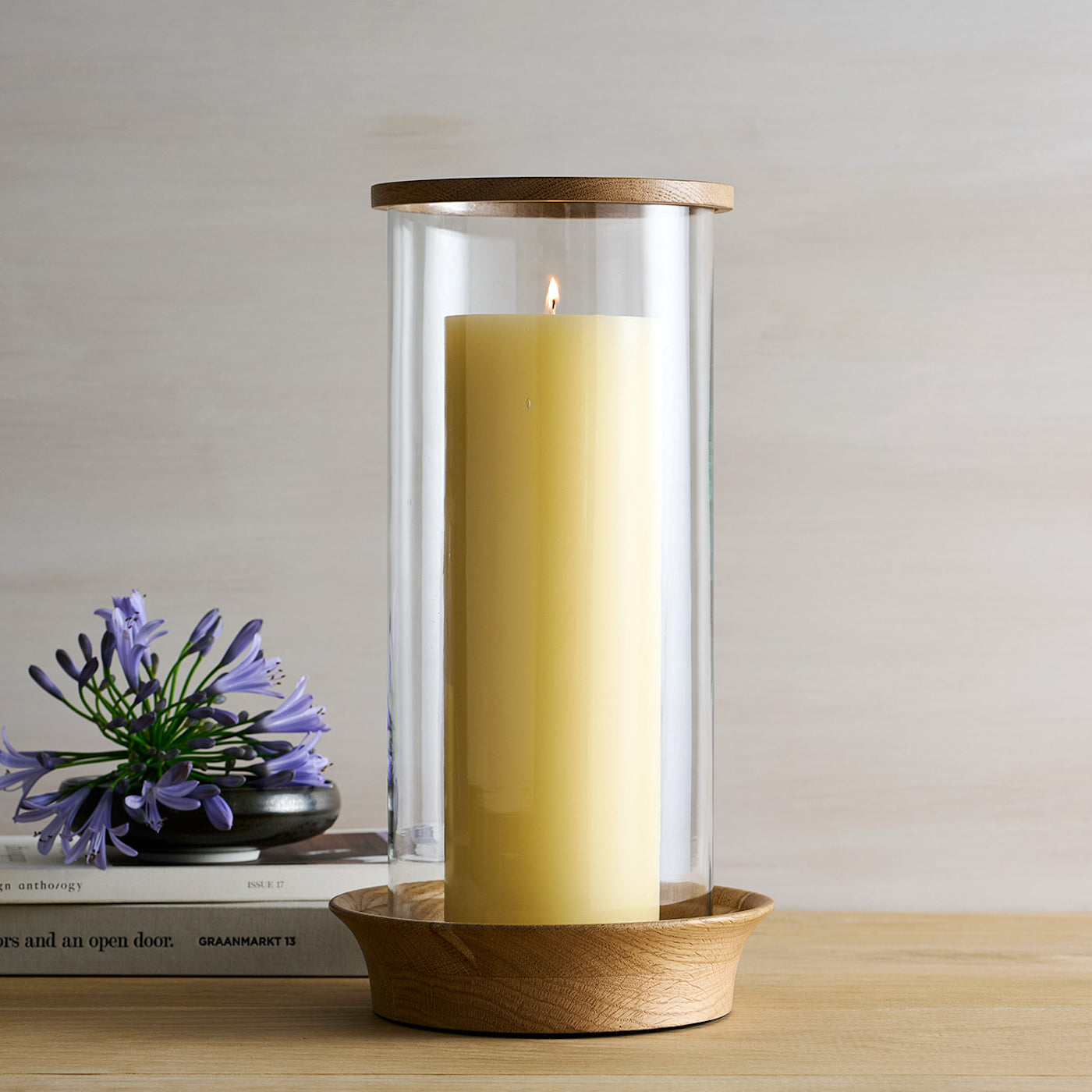 Candle in a glass holder with wooden base on a table