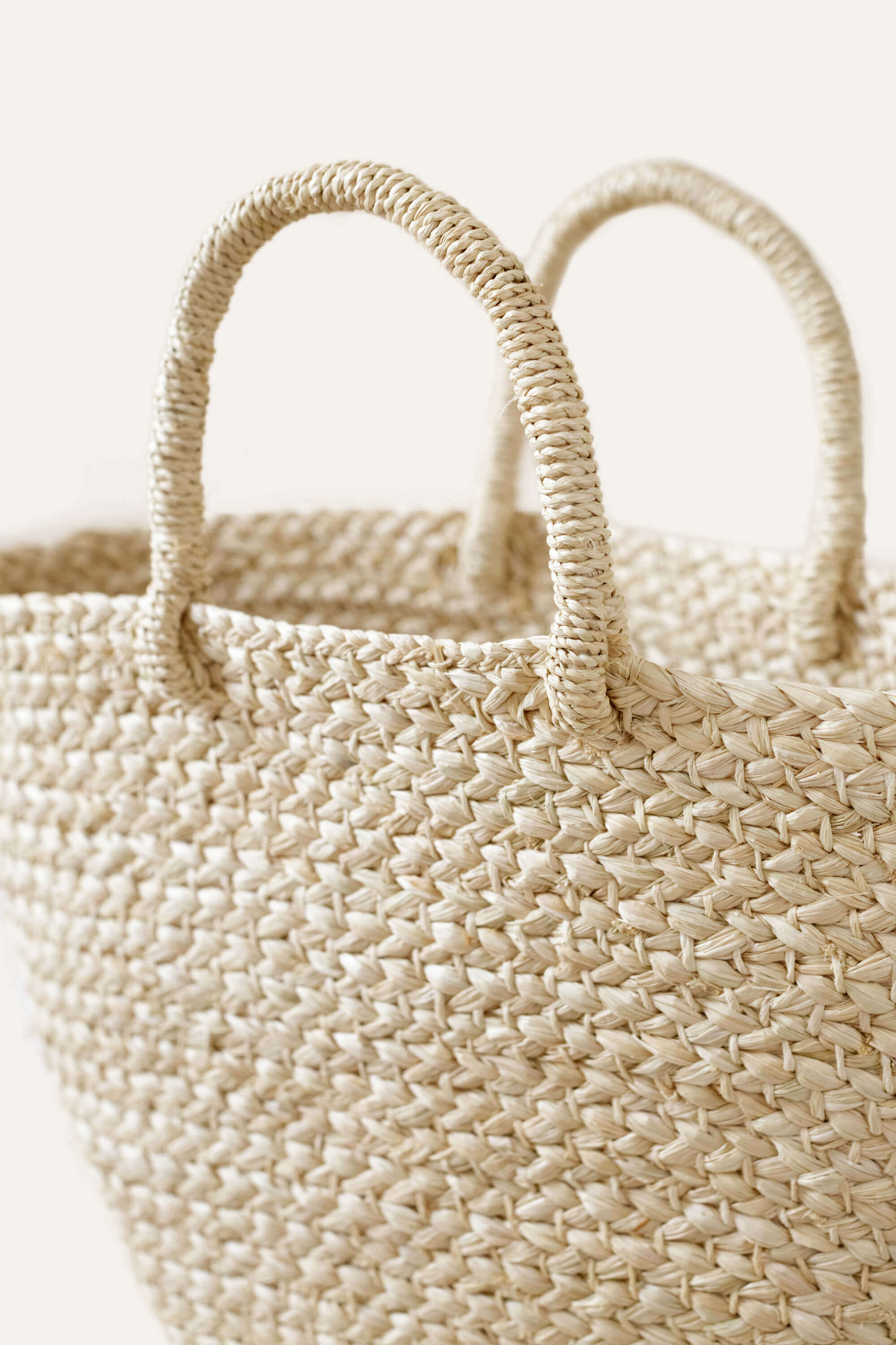 Up close view of a natural-colored braided raffia day bag with sturdy handles.