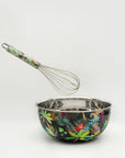 Metal mixing bowl with colorful leaf pattern and matching whisk on a white background