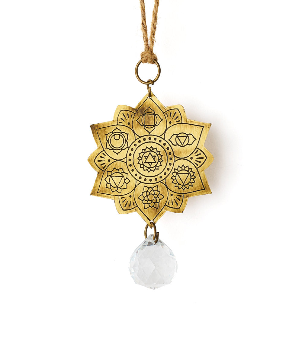 A brass suncatcher with a engraved lotus flower design and a glass bead pendant hanging from a cord