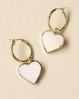 Heart-shaped earrings with gold hoops on a beige background