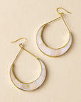 Pair of gold hoop earrings with white stone inlay on a beige background