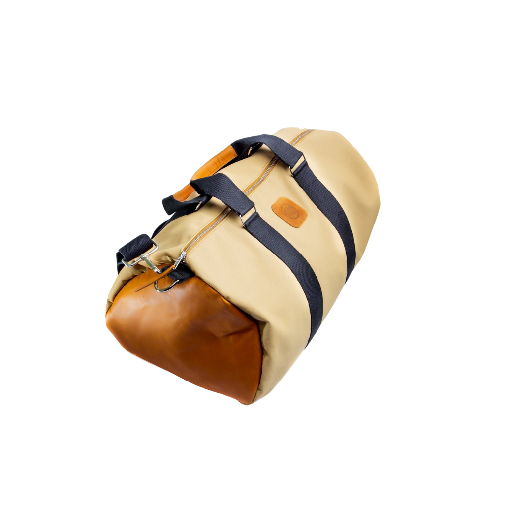 A beige and brown duffel bag with black straps and a tan leather bottom, standing upright on a plain background.