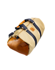 A beige and brown duffel bag with black straps and a tan leather bottom, standing upright on a plain background.