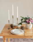 Dining table set with white plates, silverware, and a vase of flowers.