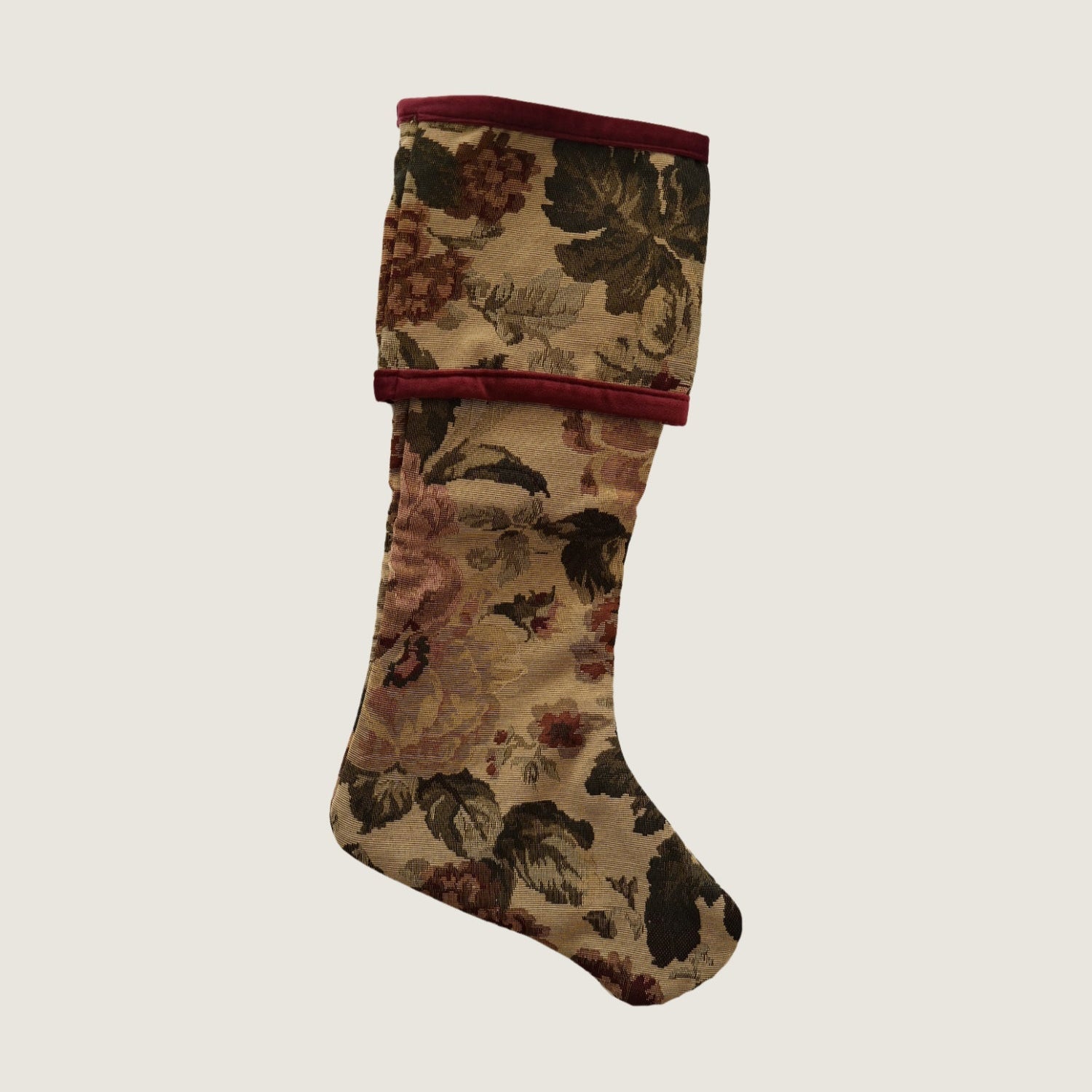 A reversible Christmas stocking featuring a floral tapestry design on one side and a solid red color with a floral pattern on the other, displayed against a white background