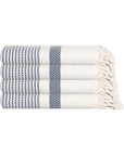 Folded white and navy striped towel with tassels on a white background
