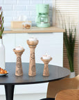 Decorative wooden candle holders with candles on a table in a kitchen setting.
