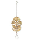 A brass suncatcher with an embossed flower design and a teardrop crystal pendant, hanging from a cord.