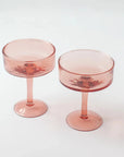 A pair of pink, handblown hammerd coupe cocktail glasses displayed against a white background