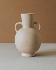 A beige ceramic vase with two handles, a rounded body, and a narrow neck, placed against a neutral background.