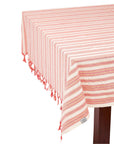 A magenta and white striped tablecloth laid out on a table with a fringe detail at the edge