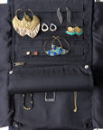 All jewelry shown in a jewelry roll travel case with chevron pattern, unrolled to show compartments for earrings, rings, and necklaces, with jewelry items like earrings, rings, and necklaces organized within it.