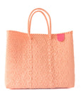 Peach-colored woven tote bag with a pink tag on a white background
