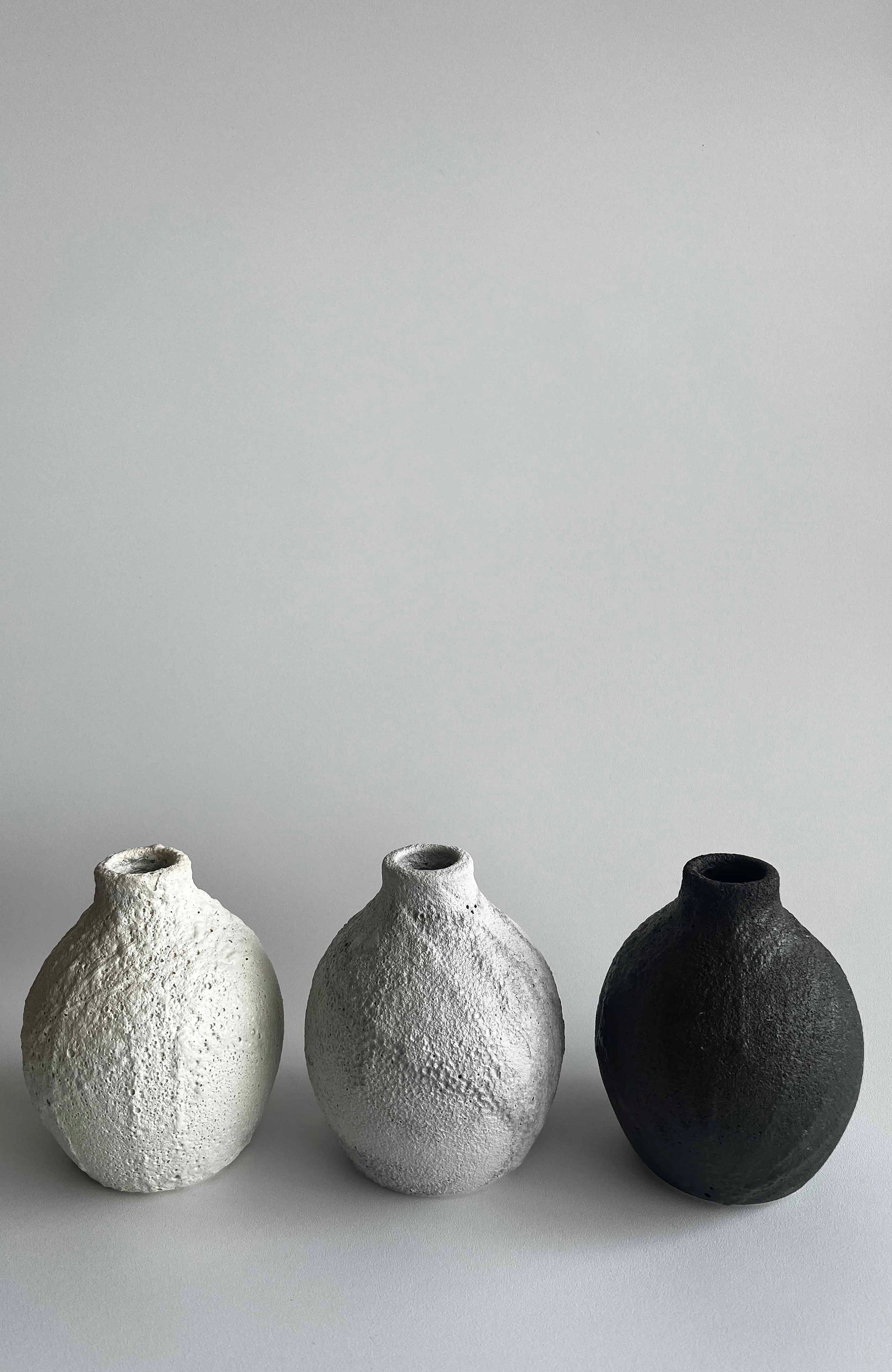Three textured ceramic vases on a light gray background