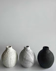 Three textured ceramic vases on a light gray background