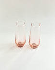 Two rose gold highball glasses on a white background