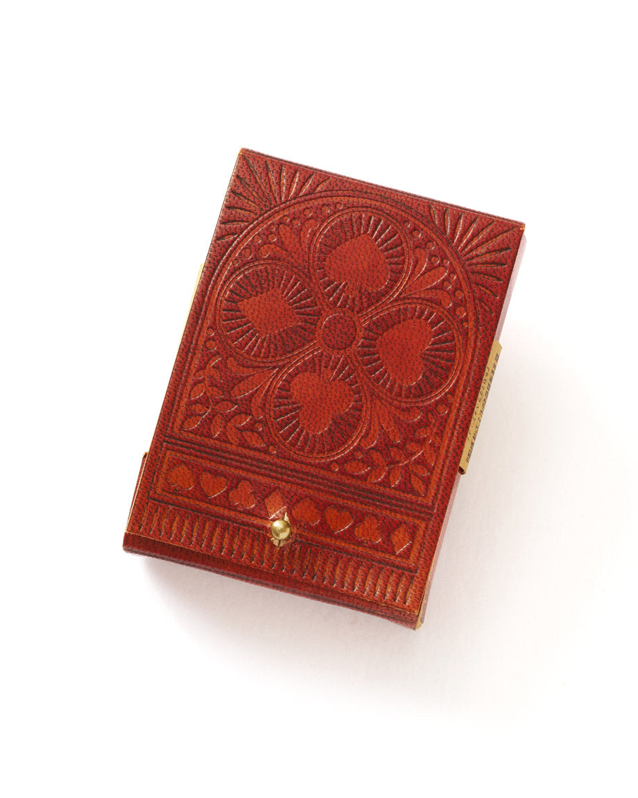 A closed embossed leather box in brown color with intricate floral patterns on the cover, likely to contain playing cards.
