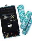 A green jewelry roll travel case with chevron pattern, unrolled to show compartments for earrings, rings, and necklaces, with jewelry items like earrings, rings, and necklaces organized within it.