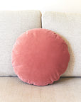Pink circular pillow on a beige couch
