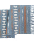 Blue woven blanket with pattern and fringes on a white background