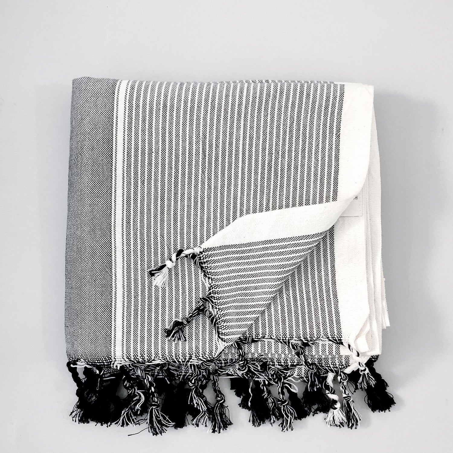 A grey striped Turkish towel with fringes displayed on a white background