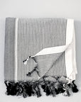 A grey striped Turkish towel with fringes displayed on a white background