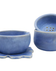 A set of blue ceramic coffee dripper and tea maker accessories, including a cup, a dripper, and a coaster.