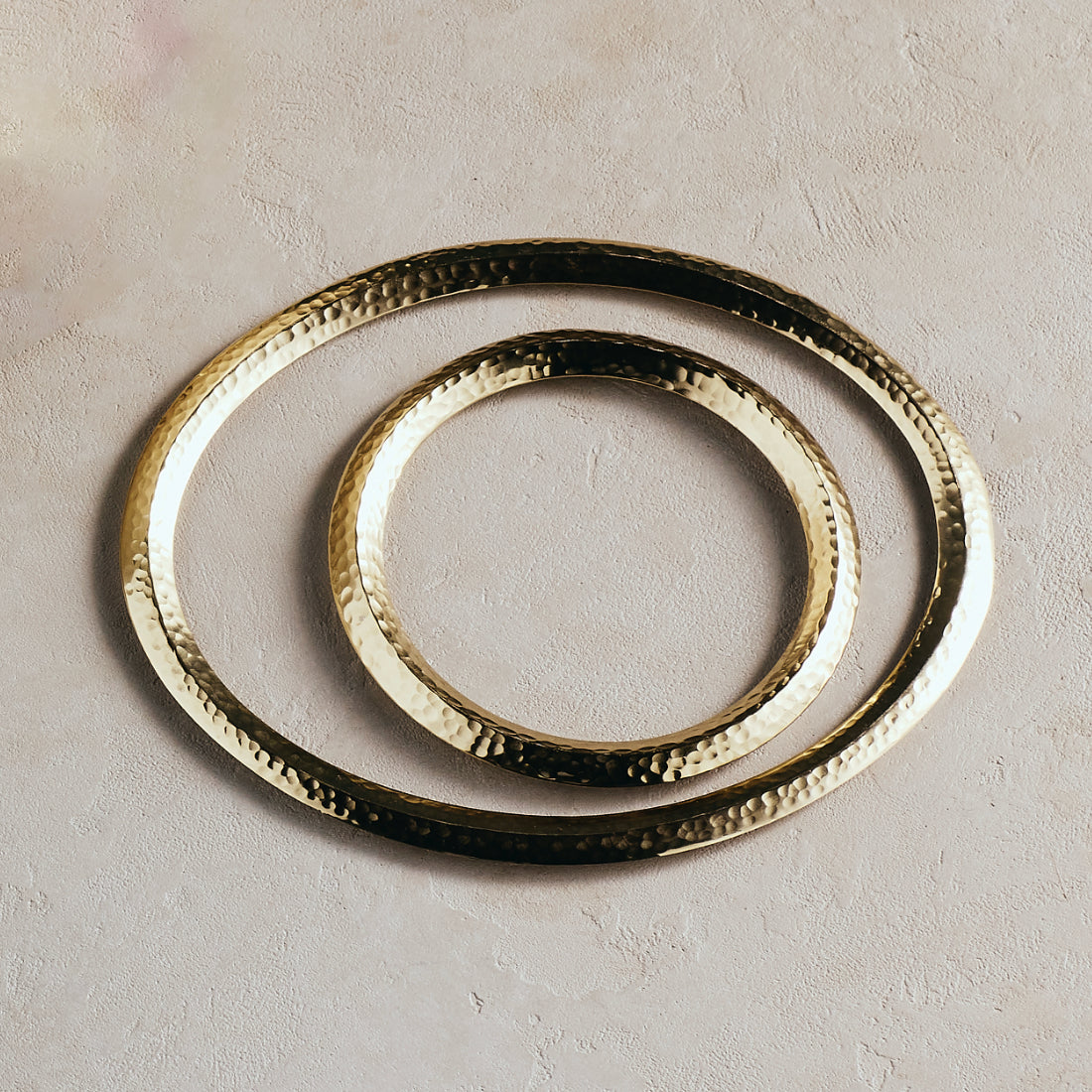Three gold trivets of different sizes on a beige background