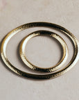 Three gold rings of different sizes on a beige background