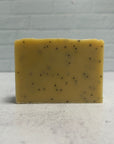 Yellow soap bar with black specks on a gray surface and background