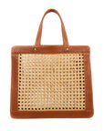 A brown leather tote bag with rattan cane webbing and leather handles.