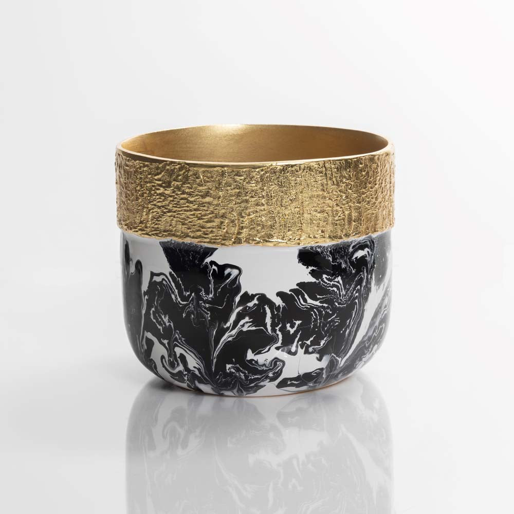 Ceramic cup with gold rim and black abstract design on a white background