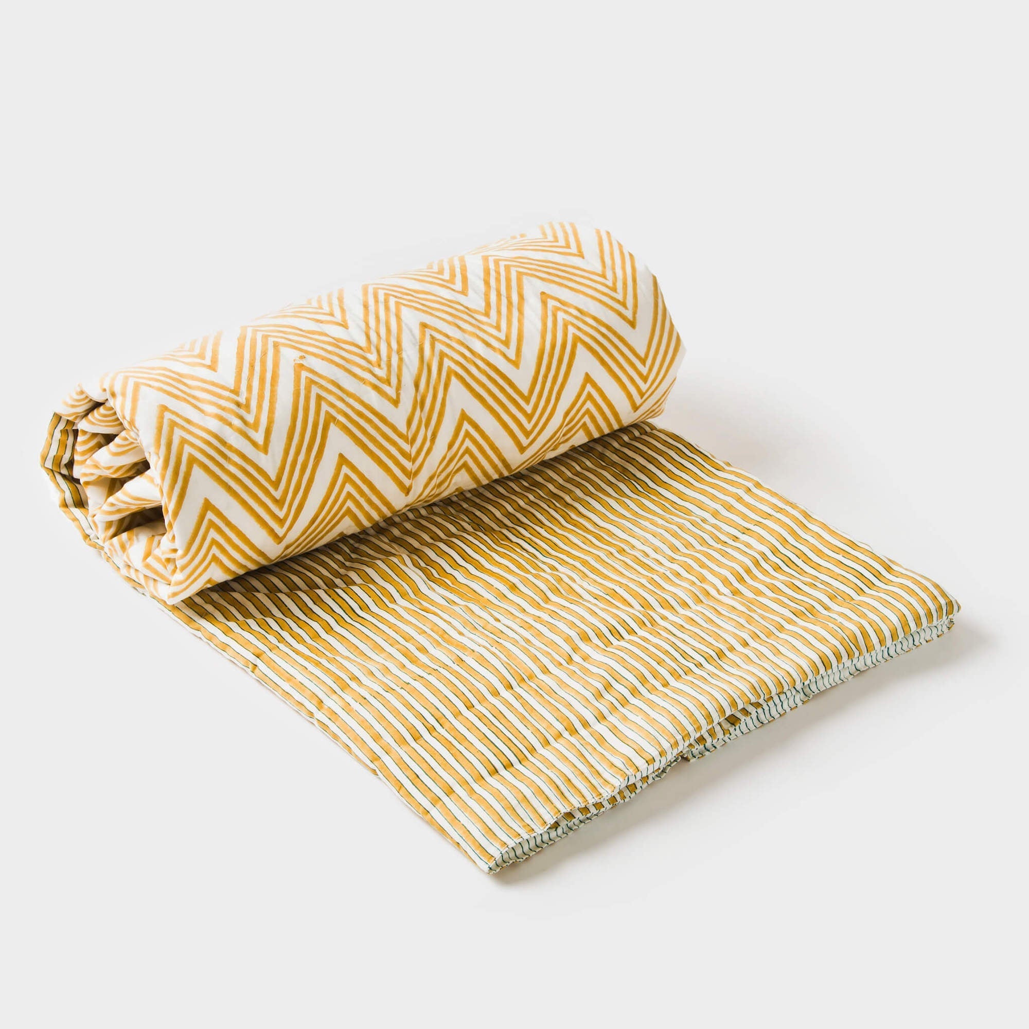 A rolled-up yellow and white striped throw with a zigzag pattern, partially unrolled to show the texture and design