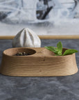 Wooden tray and reamer with green leaves and small items on a gray surface