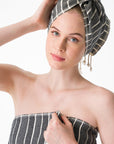 Woman wearing a black and white patterned towel on her head and shoulders against a white background