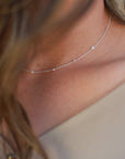 A model wearing a sterling silver choker necklace with freshwater pearls layered throughout, measuring 16 inches in length.