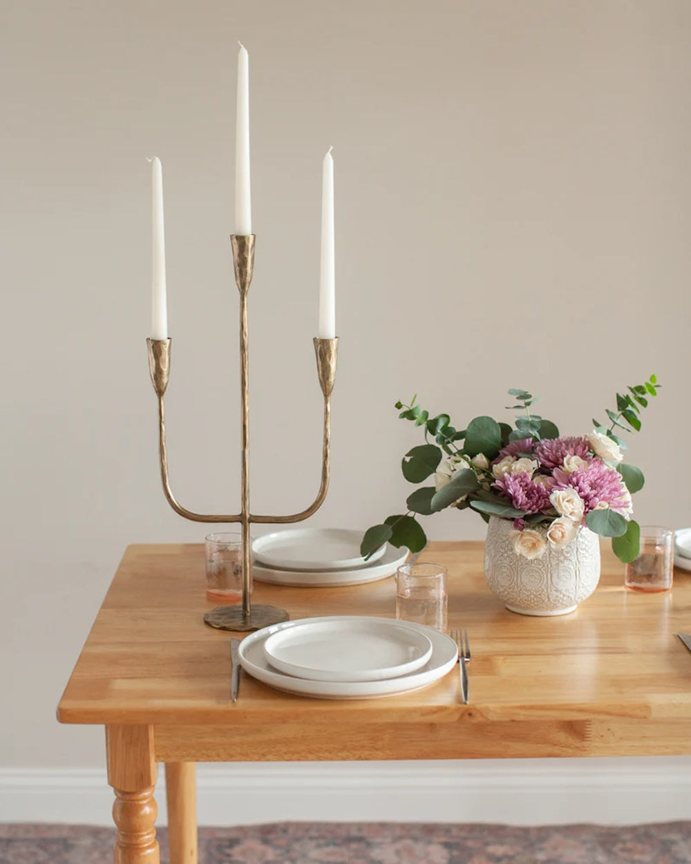 Gold candelabra with white candles on a table set for dinner.