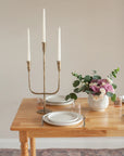 Gold candelabra with white candles on a table set for dinner.