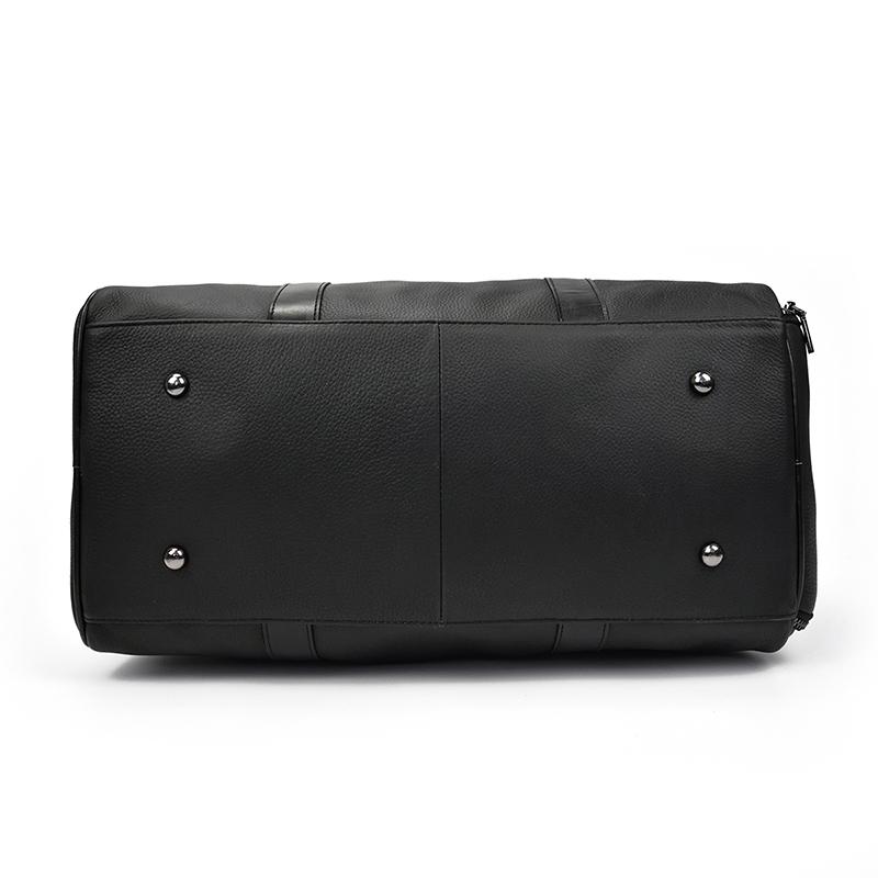 The bottom of a black leather weekender bag.
