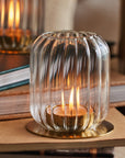 Clear glass candle holder with a lit candle on top of books